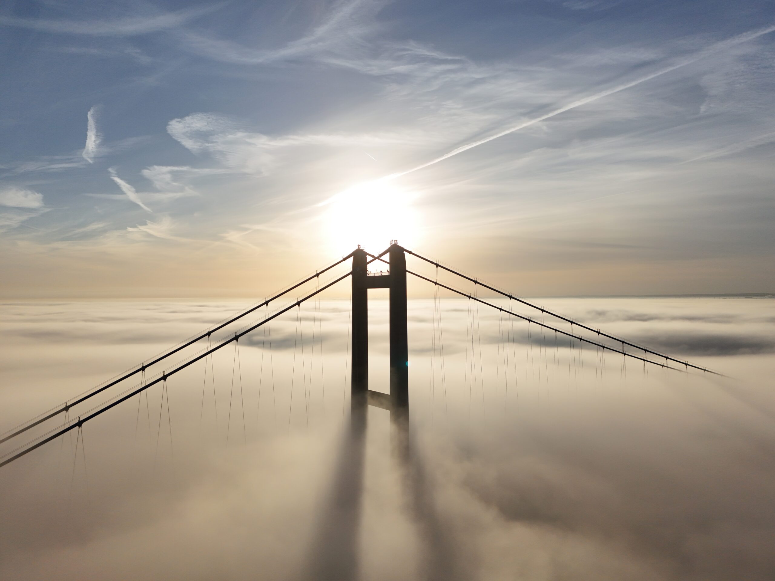 Suspension bridge with cables and clouds in the background